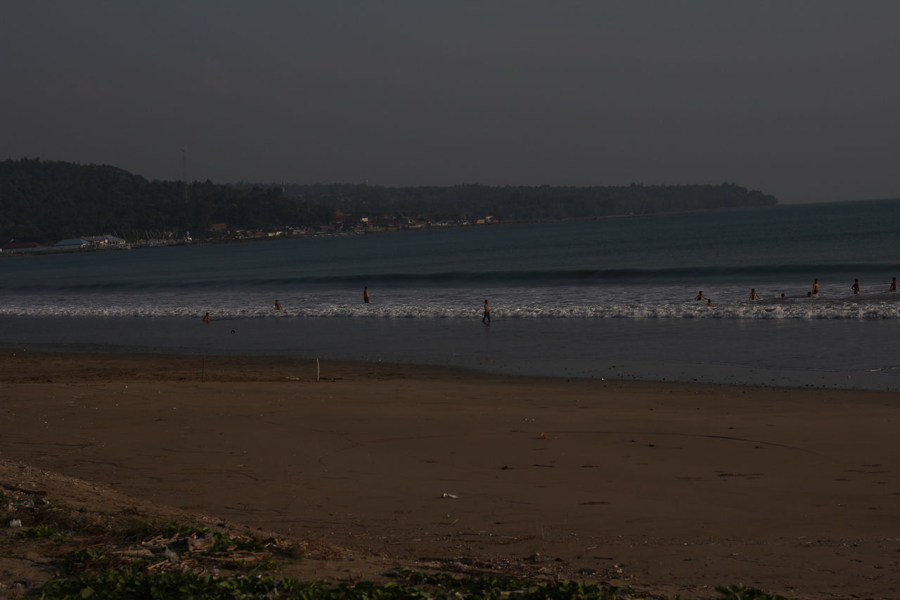 GROUP OF PEOPLE ON BEACH AGAINST SKY