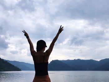 Rear view of woman standing against cloudy sky at dusk