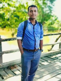 Portrait of young man standing against trees