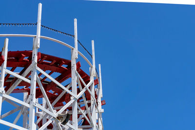 Low angle view of ferris wheel against clear blue sky