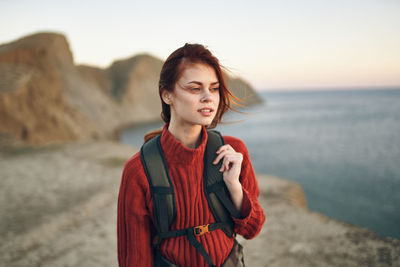 Young woman standing at beach during sunset