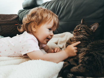 Cute girl touching cat on sofa