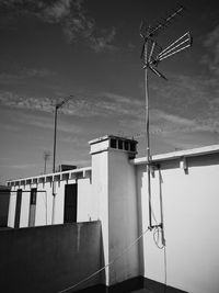 Low angle view of telephone pole against building against sky