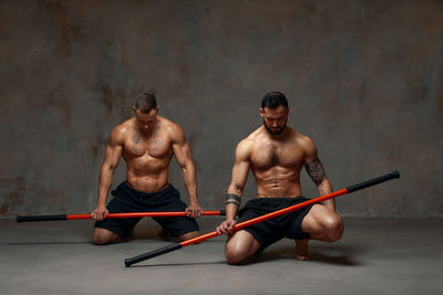 Men holding combat stick in gym