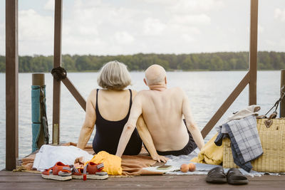 Senior couple sitting on gazebo while looking at river against sky