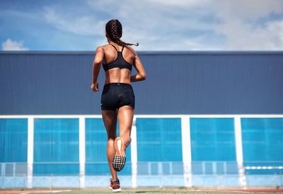 Young woman running against sky