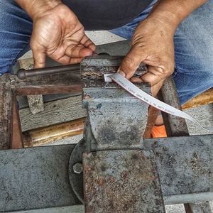 Midsection of man working on metal and cable