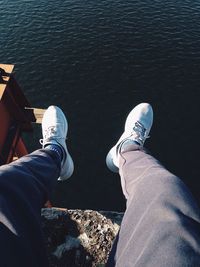Low section of man sitting against lake