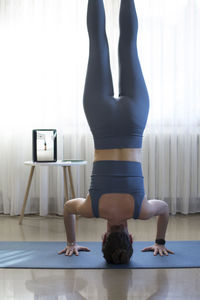 Midsection of woman with arms raised on floor