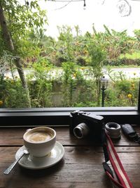 Coffee cup on table against trees