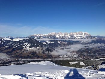 Scenic view of snow covered mountains against blue sky