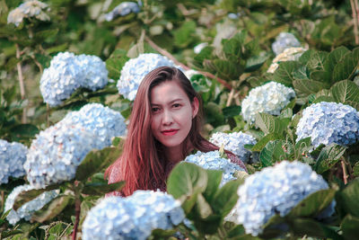 Portrait of smiling young woman against plants