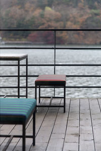 Empty chairs and tables by lake