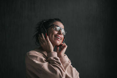 Portrait of smiling young woman against black background