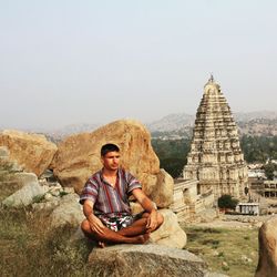 Man meditating on rock against temple