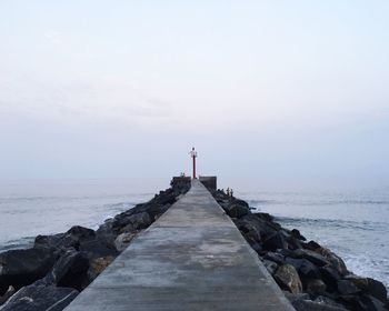Groyne in sea against sky during sunset