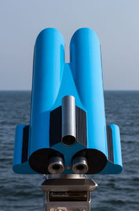 Close-up of coin-operated binoculars against sea