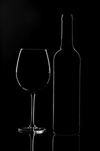 Glass of wine bottles against black background