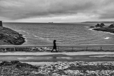 Woman walking on road against sea during winter