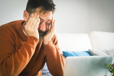 Young man using mobile phone while sitting on bed at home