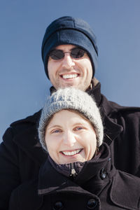 Low angle portrait of smiling couple wearing warm clothing against sky