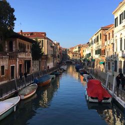 Boats moored in canal along buildings