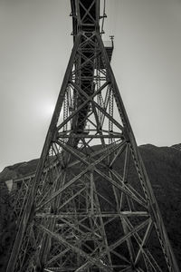 Low angle view of electricity pylon on field against sky