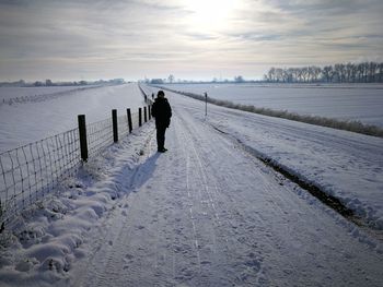 Rear view of man walking on snow covered land