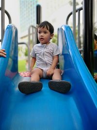 Full length of boy sitting on slide