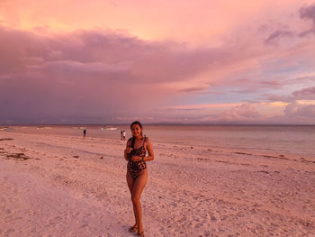 Woman on beach against sky during sunset