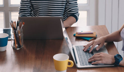 Midsection of man using laptop on table