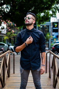 Young man wearing sunglasses while standing on footpath 