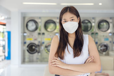 In the self-service laundry with dryer machines in the backdrop, a young woman enjoys clean ironed .