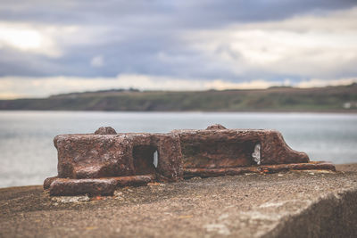 Close-up of rusty metal by sea against sky