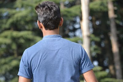 Rear view of man standing against trees