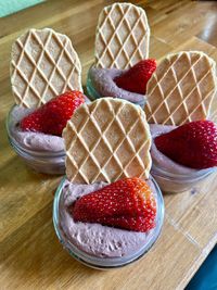 Close-up of pudding with strawberries and waffle in a small bowl on a wooden table