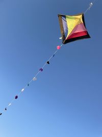 Low angle view of flags against clear blue sky