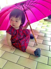 Cute girl looking away while sitting on tiled floor