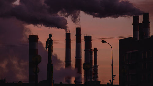 Smoke emitting from factory against sky during sunset