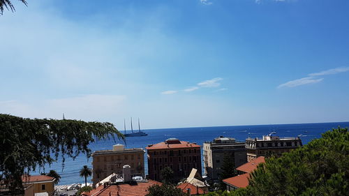 Buildings by sea against blue sky