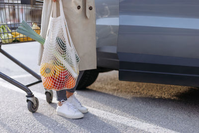 Girl holding mesh shopping bag with organic fruits and vegetables. zero waste, plastic free concept