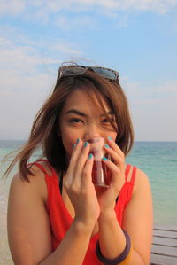 Portrait of beautiful woman on beach against sky