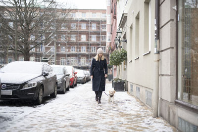 Woman with dog walking on winter street