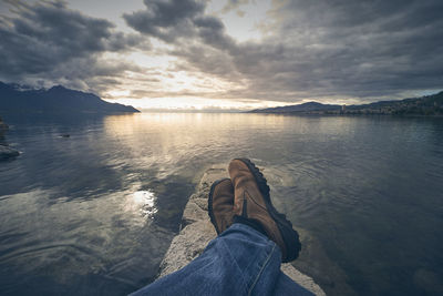 Low section of person on lake against sky