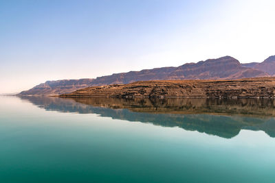 Scenic view of lake and mountains against clear blue sky