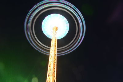 Low angle view of illuminated carousel against sky at night