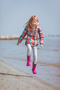 Full length of woman with arms raised on beach against sky