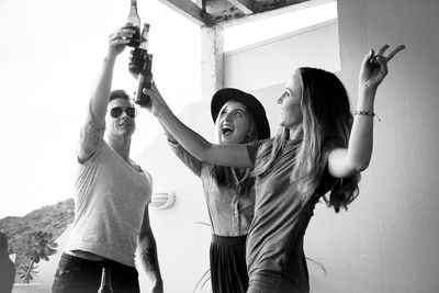 Friends toasting beer bottles against wall