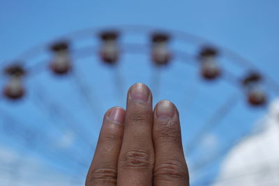 Close-up of human hand against sky