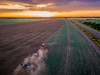 High angle view of combine harvester on field against sky during sunset